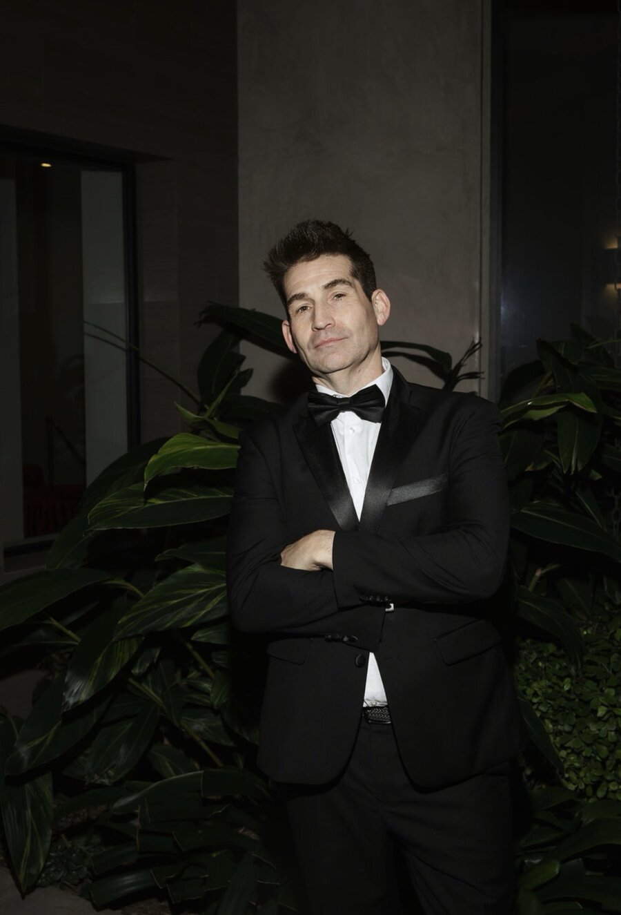 Todd in a tuxedo, arms crossed, level gaze